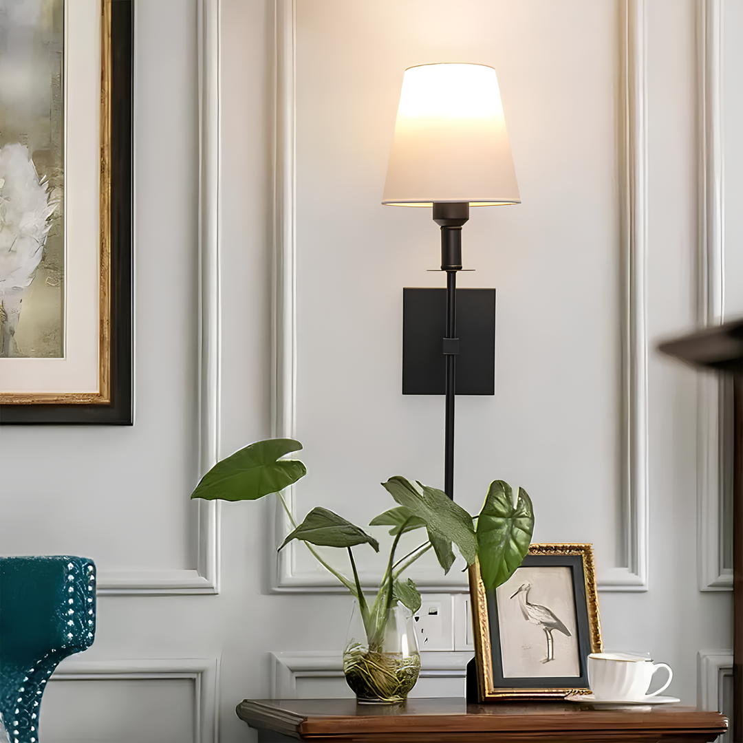 Elegante wandlamp gecombineerd met gouden en natuurlijke accenten in een kamer.
