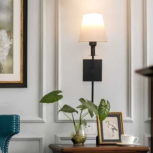 Elegante wandlamp gecombineerd met gouden en natuurlijke accenten in een kamer.
