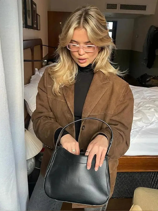 Vrouw draagt een suède dames blazer met vintage look, perfect voor een chique en tijdloze uitstraling.