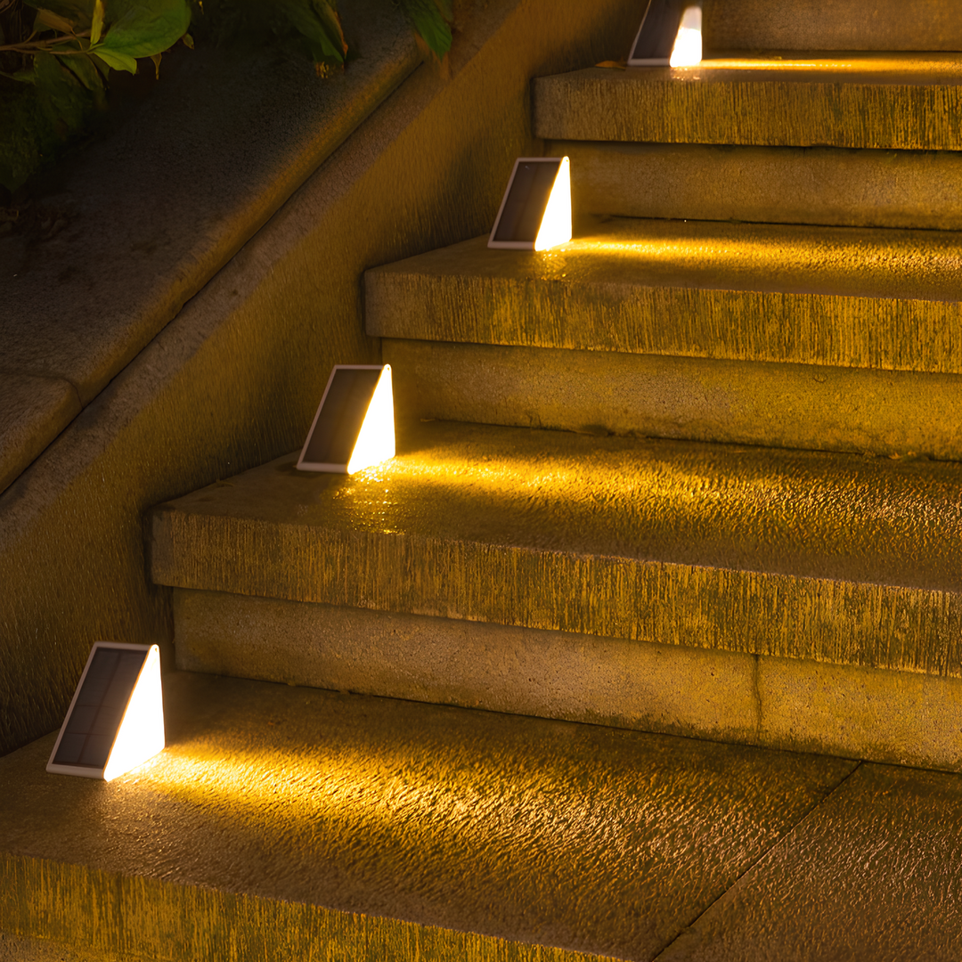 Close-up van zonne-verlichte traplamp gemonteerd langs een pad.
