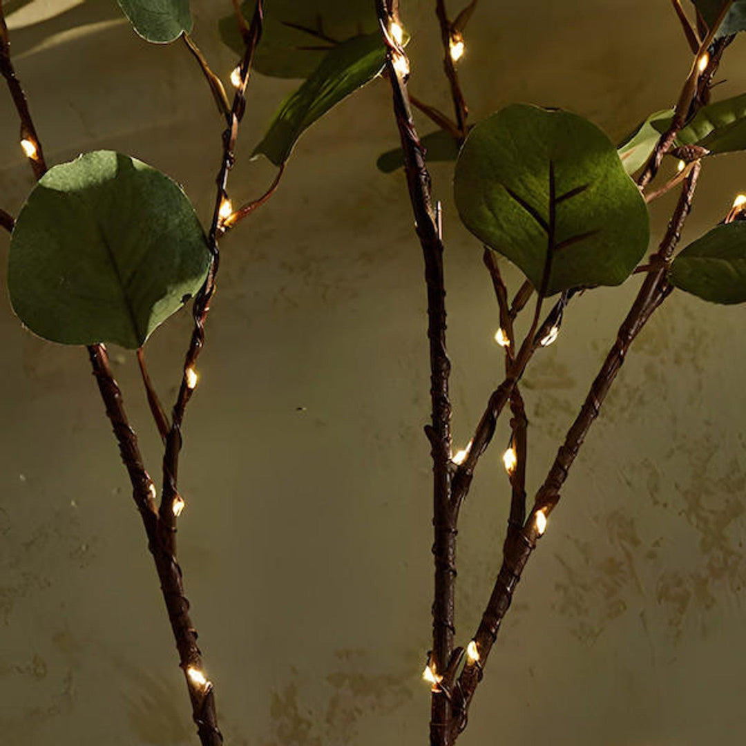Sfeervolle LED bloemenlichtjes rond een vaas met groene takken, perfect voor een gezellige en warme ambiance.
