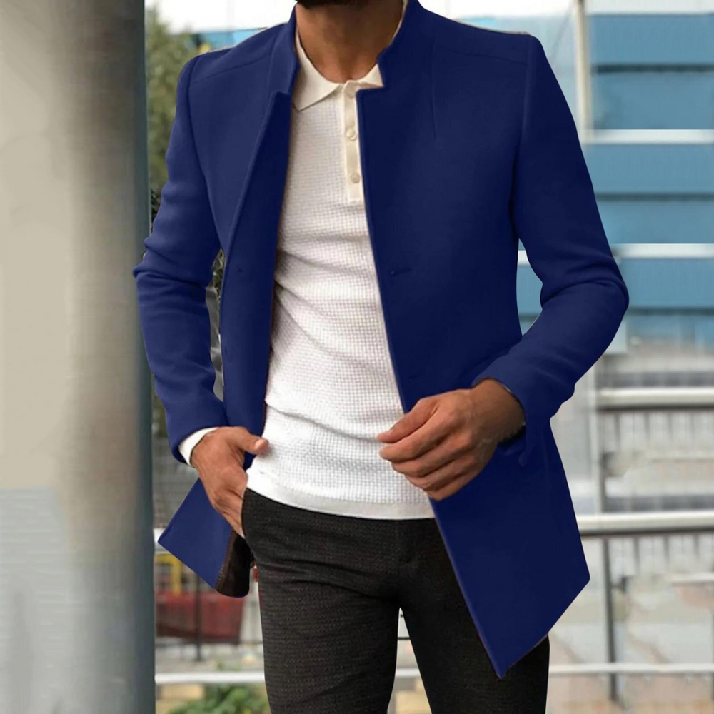 Blauw herenjack gecombineerd met een casual outfit op de achtergrond van een modern gebouw.
