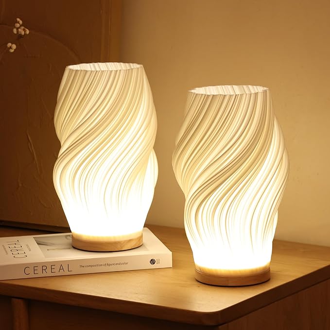 Twee Elina Tafellampen met een golvend design die een warme gloed uitstralen.
