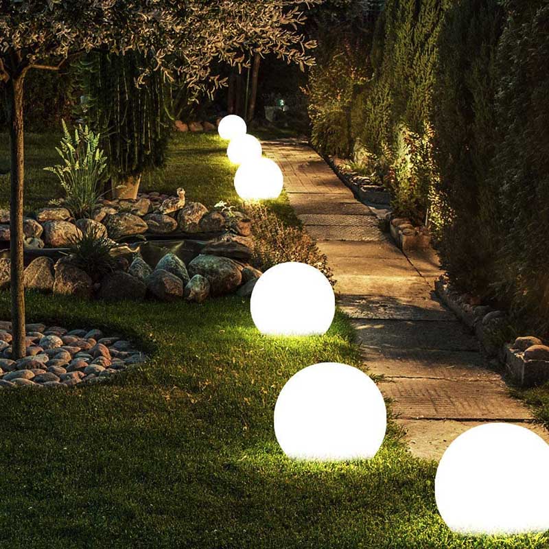 Drijvende Luna-lampen in verschillende maten bij een vijver.
