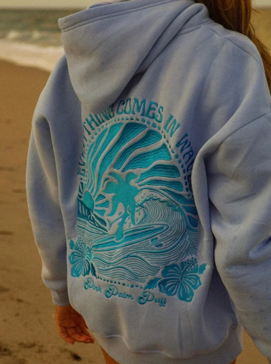 Twee vriendinnen dragen pastel hoodies onder palmbomen.