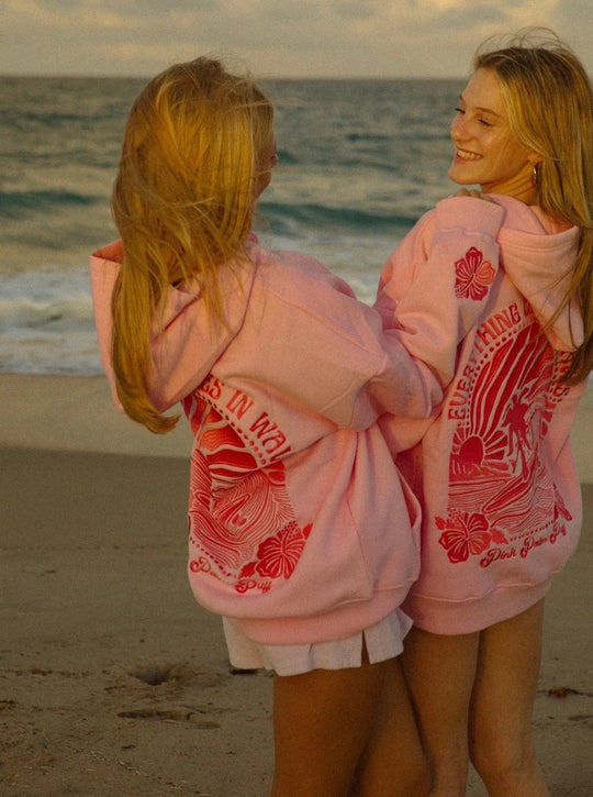 Roze hoodie met "Chasing Sunsets" design op de rug.