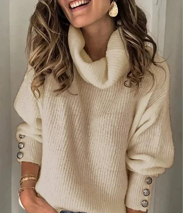 Lotte Vrouwelijke warme coltrui met een gebreid ontwerp en knopen op de mouwen. Deze trui biedt comfort en stijl, perfect voor een gezellige look tijdens de koudere maanden.