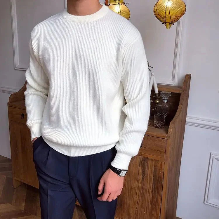 Zwarte trui gecombineerd met een nette beige broek in een elegante setting.
