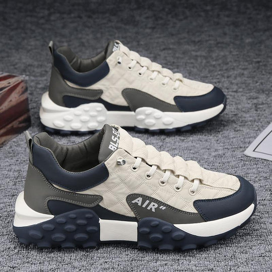 Beige en grijze sneakers gepresenteerd op een moderne achtergrond.
