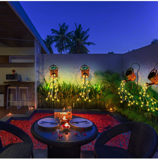 Buitendecoratie met een gieter die LED-lichtstraaltjes uitstraalt, ideaal voor sfeerverlichting in de tuin.
