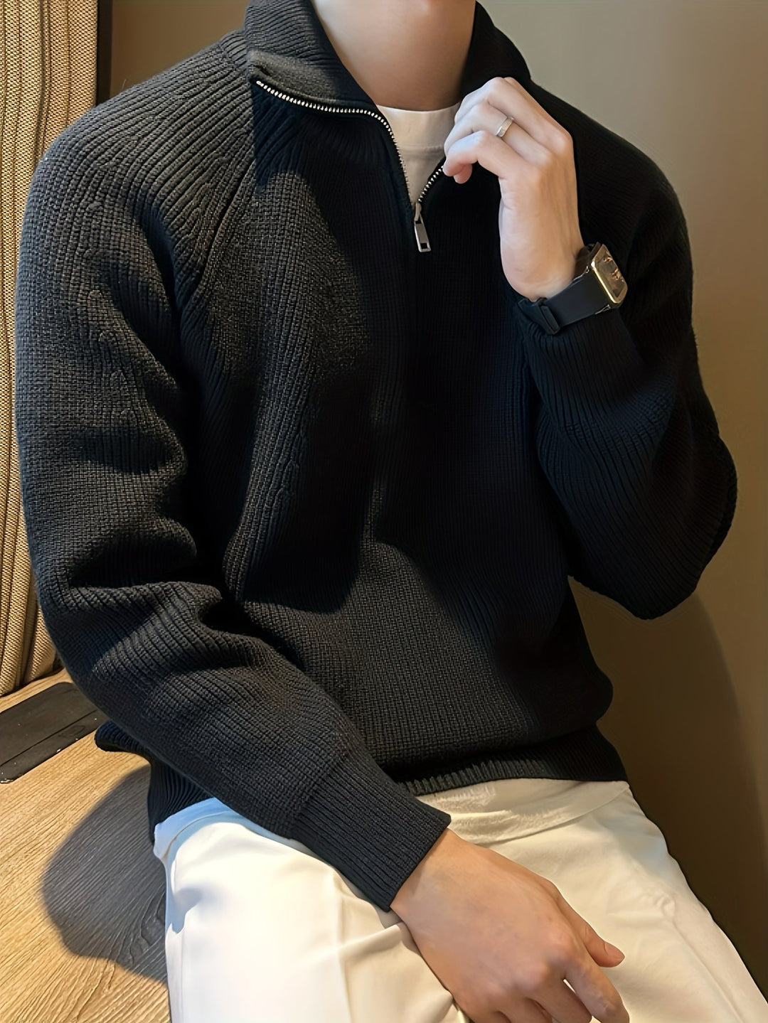Trui gecombineerd met een witte onderlaag en zwarte broek voor een elegante look.
